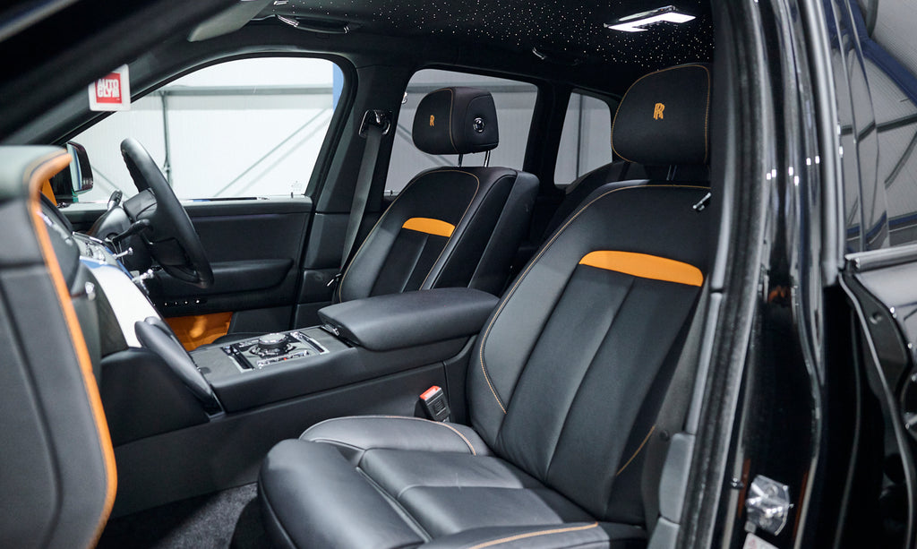 Interior of a luxury vehicle with black leather seats and orange accents.