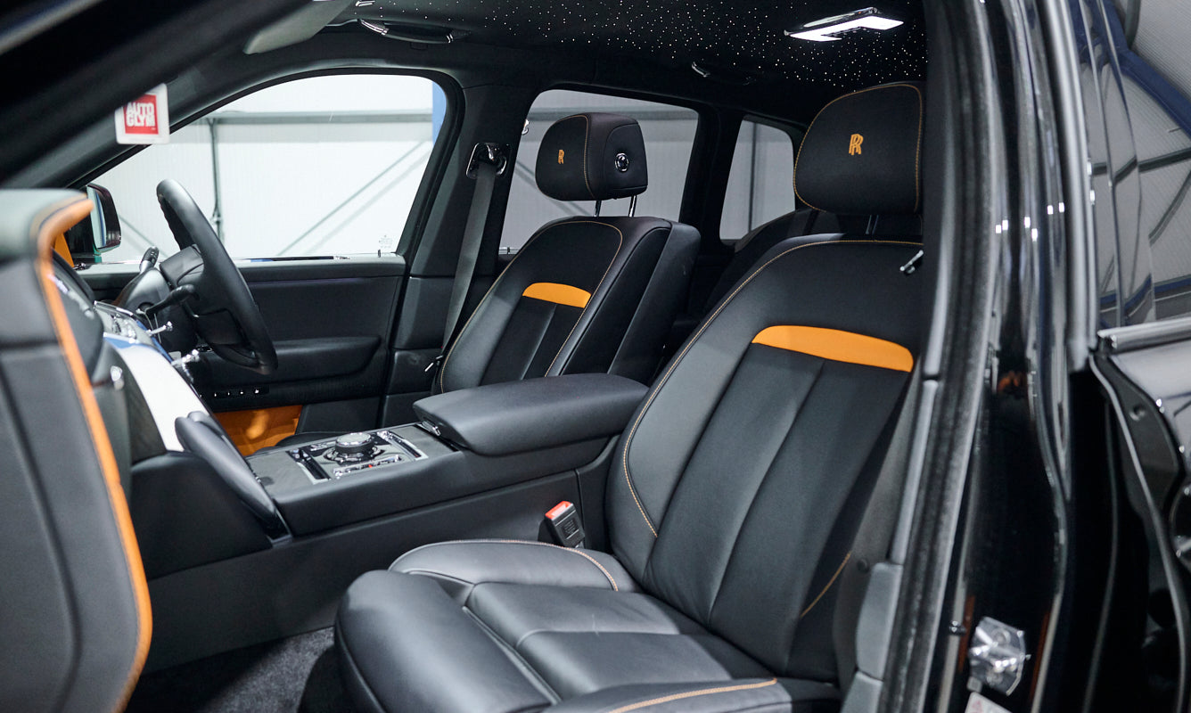 Interior of a luxury vehicle with black leather seats and orange accents.
