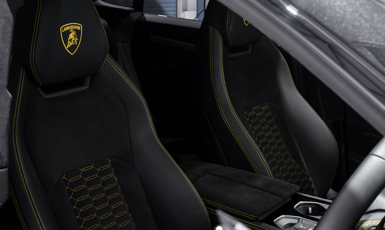 Car interior with black seats featuring a logo, likely of a luxury brand.