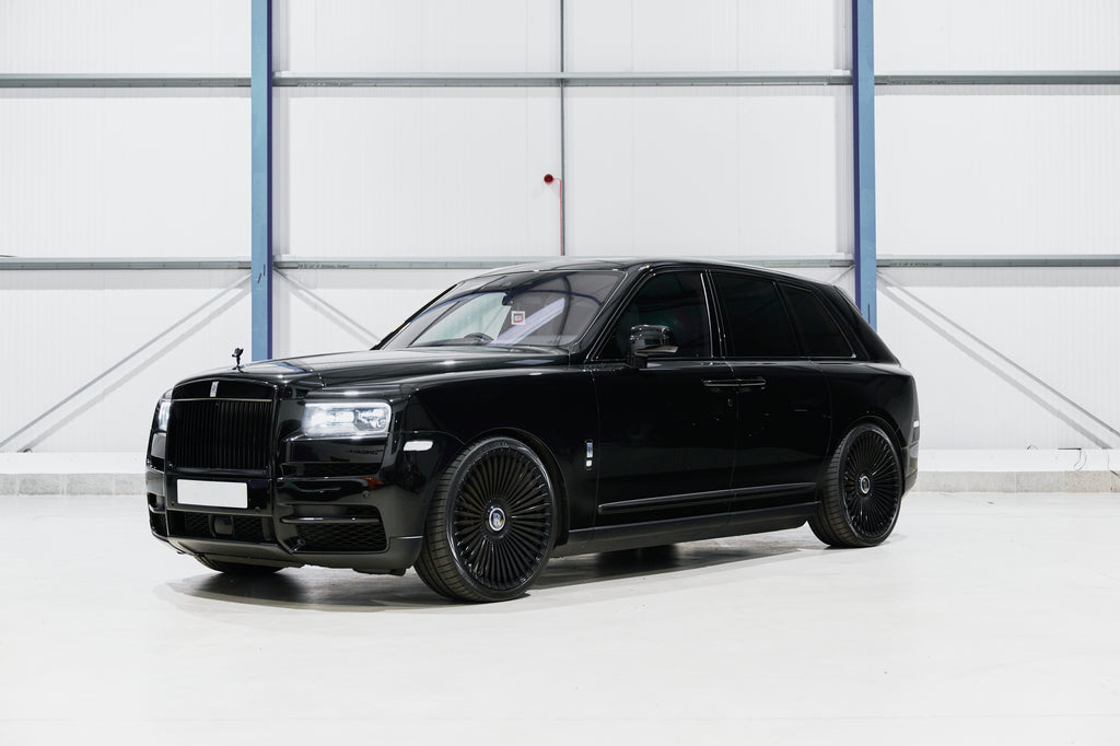 Black luxury SUV parked inside a building with a white floor and gray walls.