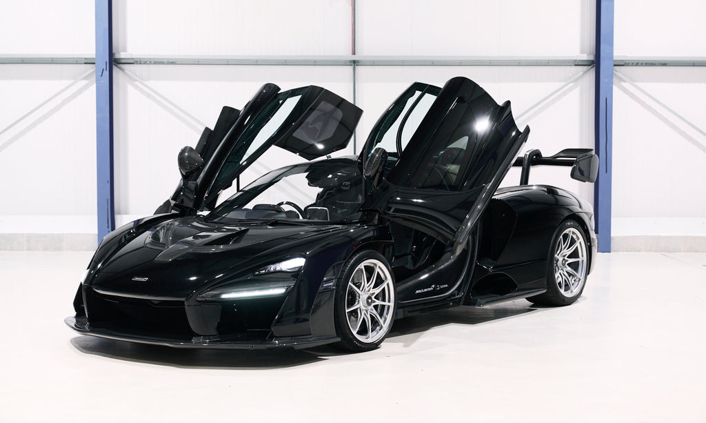 Black sports car with open doors in a showroom setting