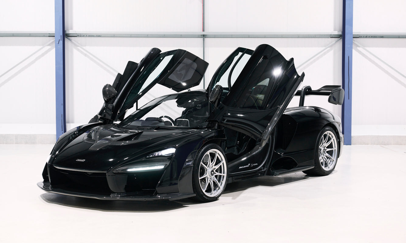 Black sports car with open doors in a showroom setting