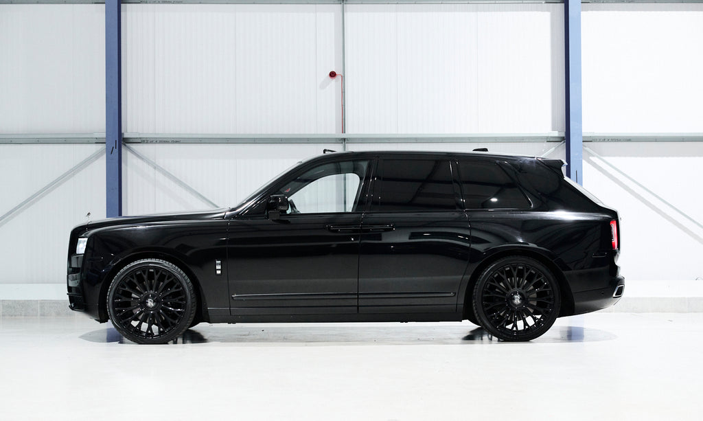 Black luxury SUV parked inside a large white warehouse.