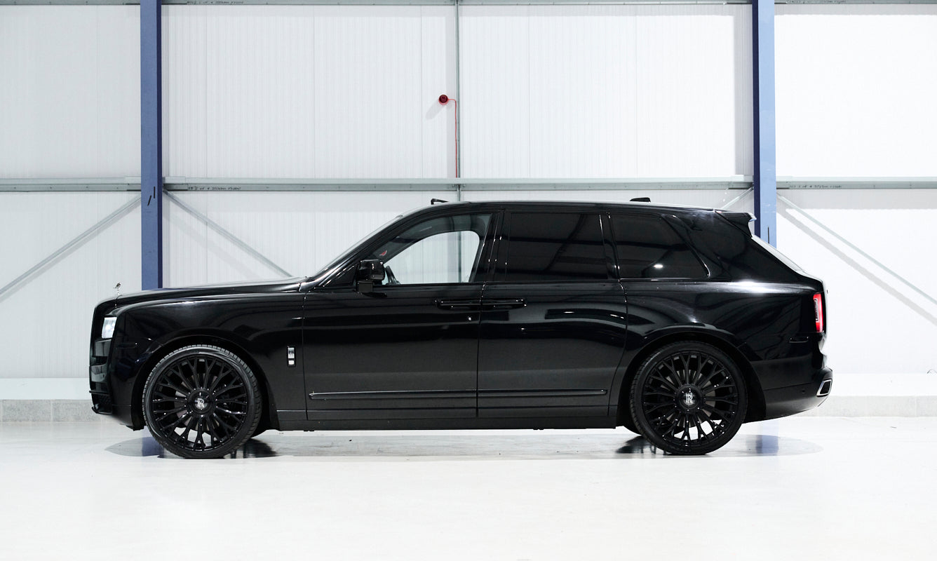 Black luxury SUV parked inside a large white warehouse.