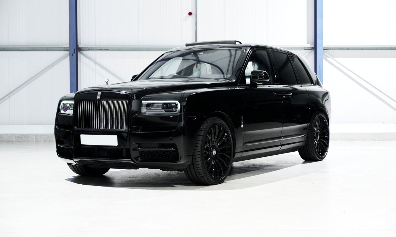 Black luxury SUV parked indoors with a white background